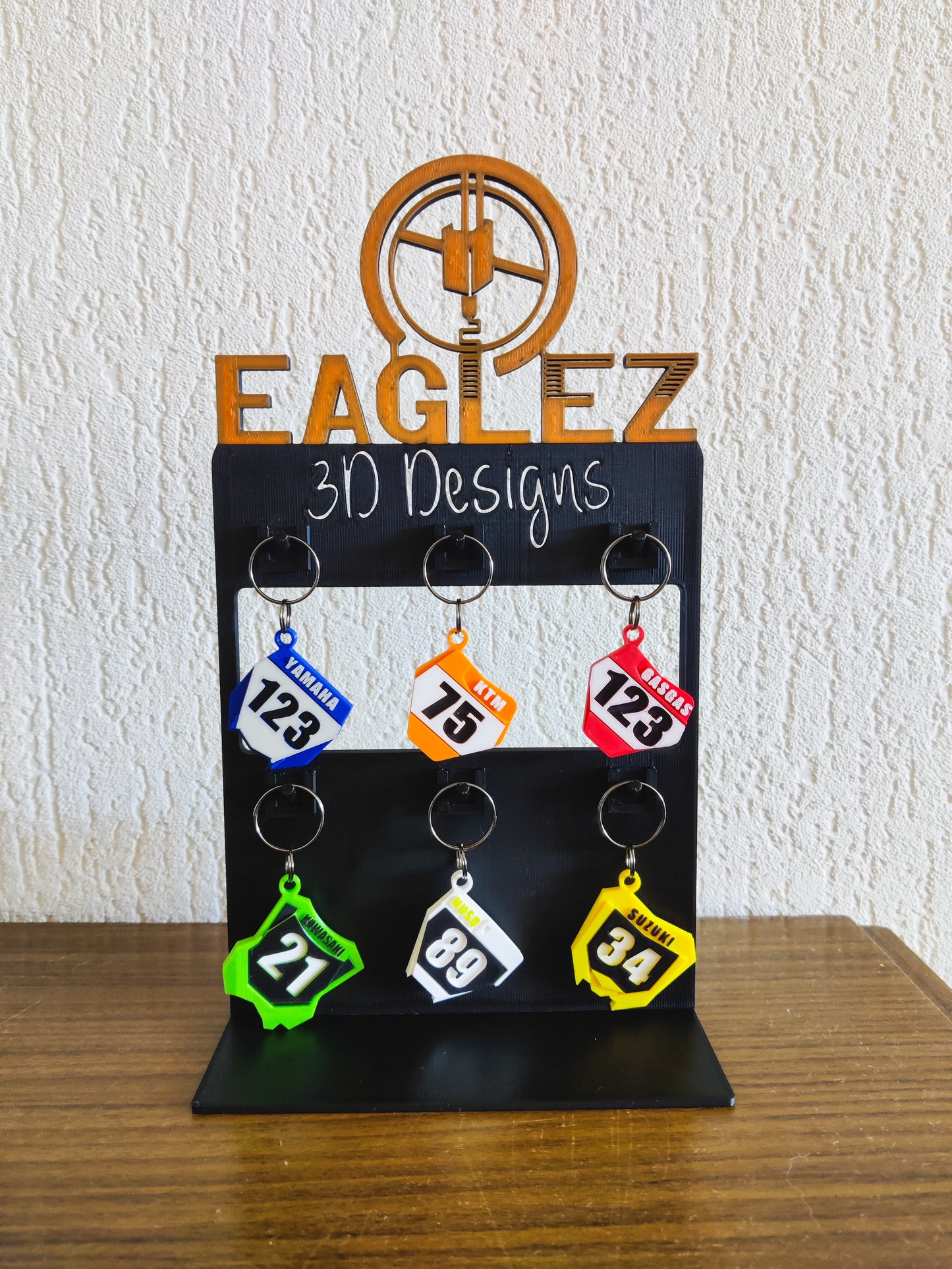 Gepersonaliseerde motocross sleutelhangers tentoongesteld op een 3D-geprinte standaard.