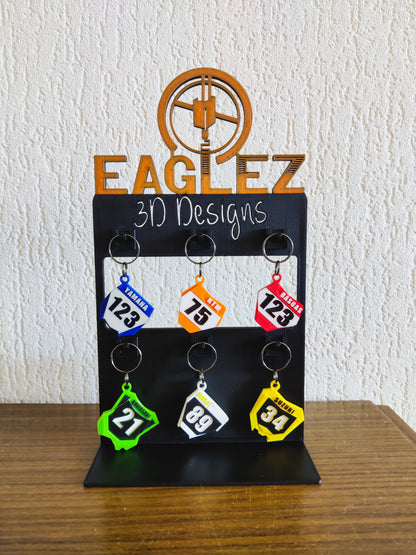 Gepersonaliseerde motocross sleutelhangers tentoongesteld op een 3D-geprinte standaard.